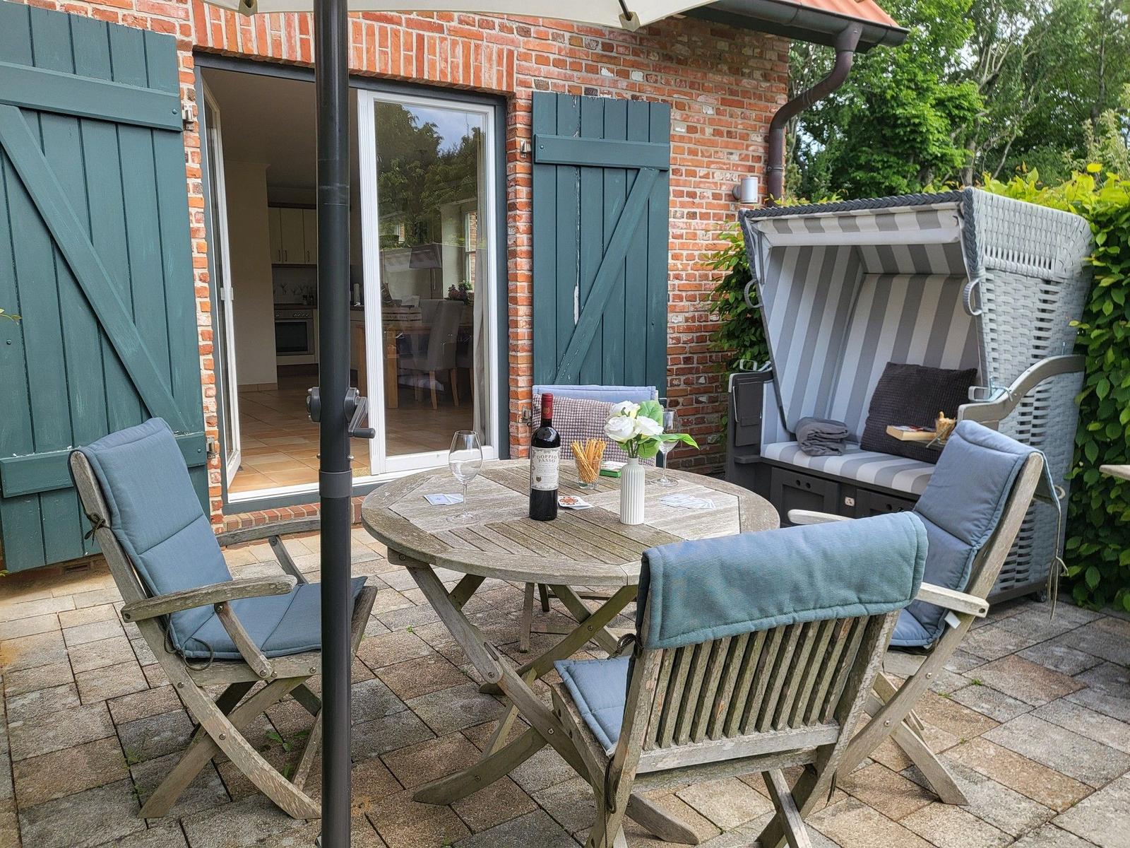 Terrasse mit Tisch, Stühlen und Strandkorb vor Backsteinhaus