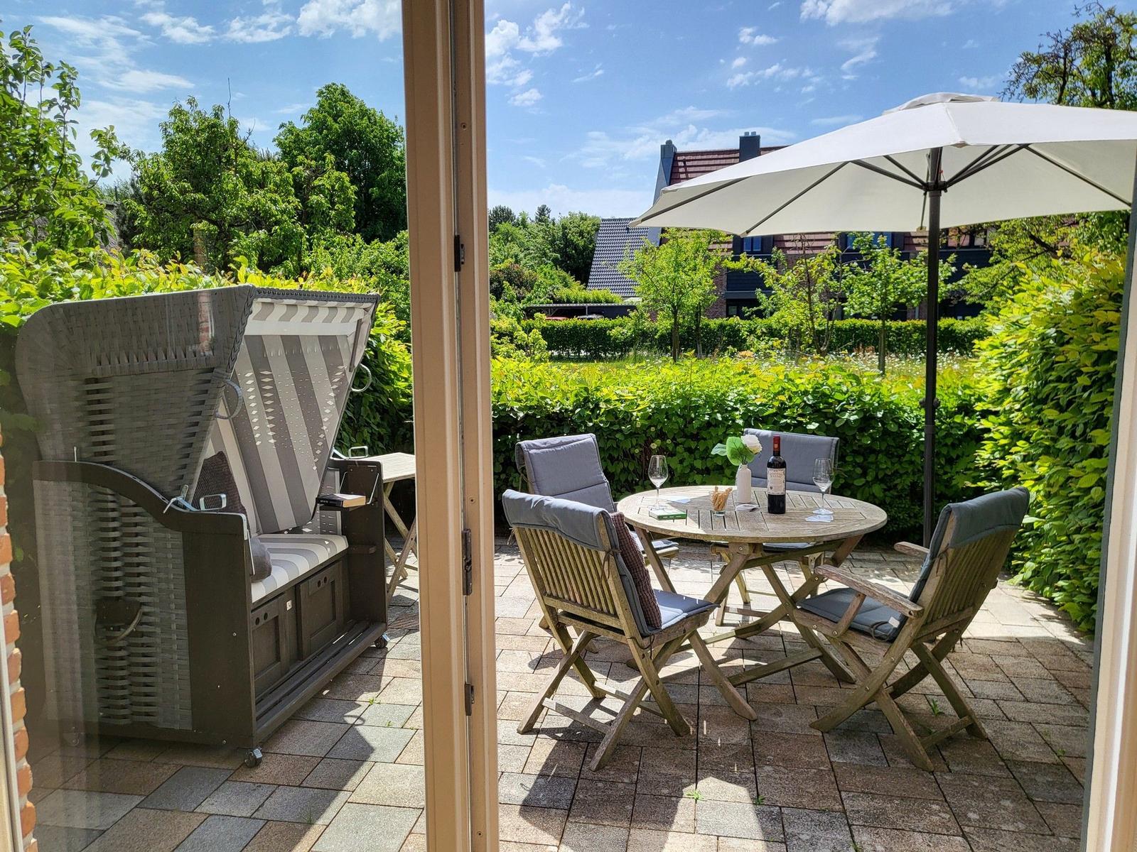 Terrasse mit Sitzgruppe, Sonnenschutz und Gartenblick.