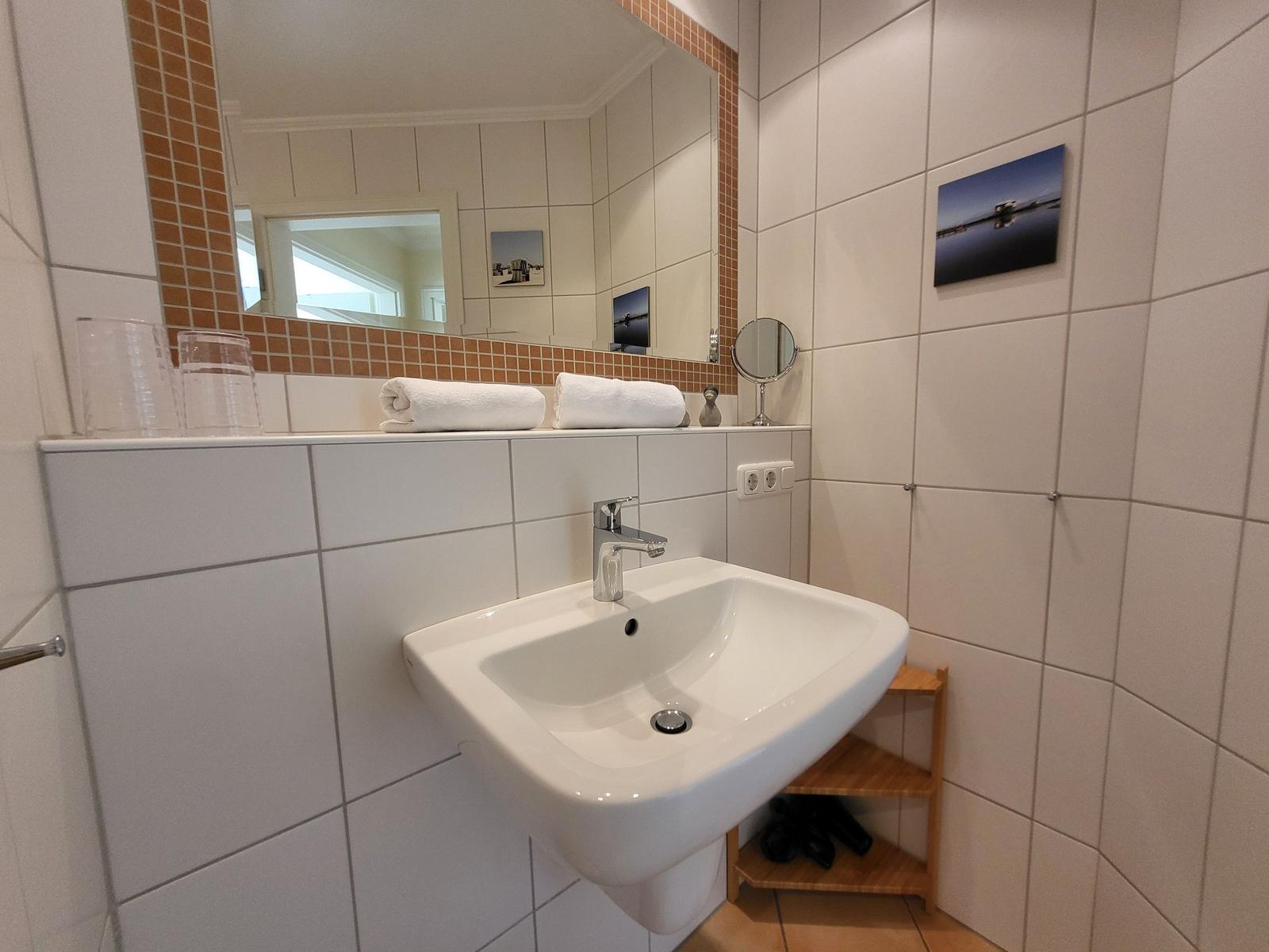 Badezimmer mit Waschbecken, Spiegel und Handtüchern.