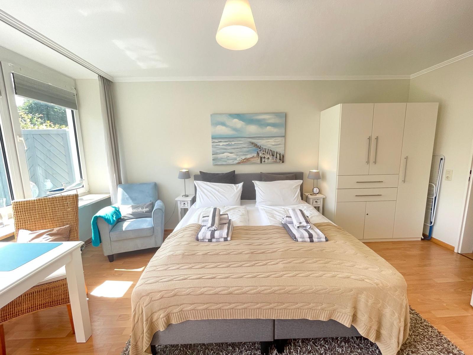 Schlafzimmer mit Doppelbett, Kleiderschrank und Fensterblick.