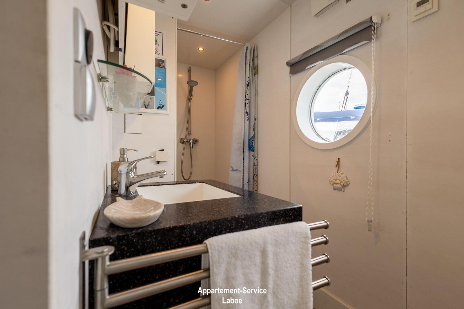 Badezimmer mit Waschbecken, Dusche und runden Fenster