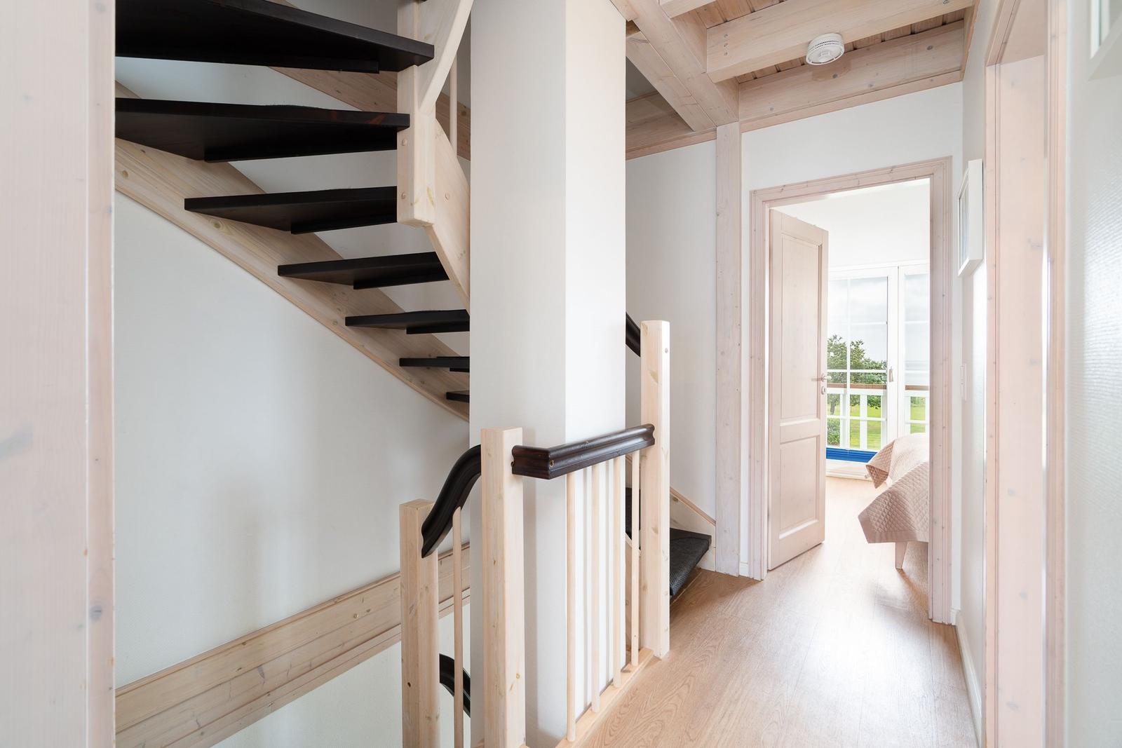 Staircase with wooden railing and view into bedroom