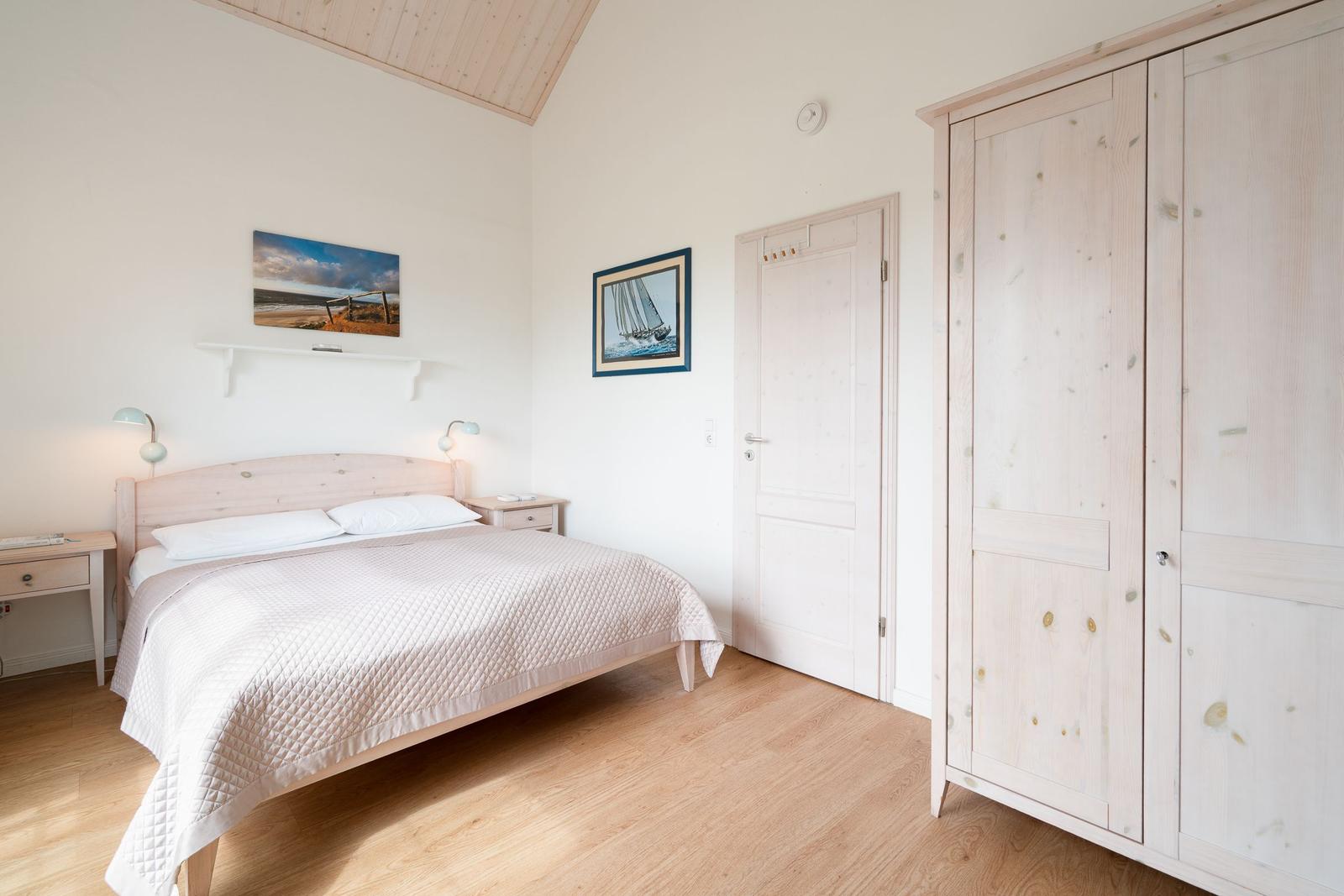 Bedroom with bed, wardrobe, and wall pictures.