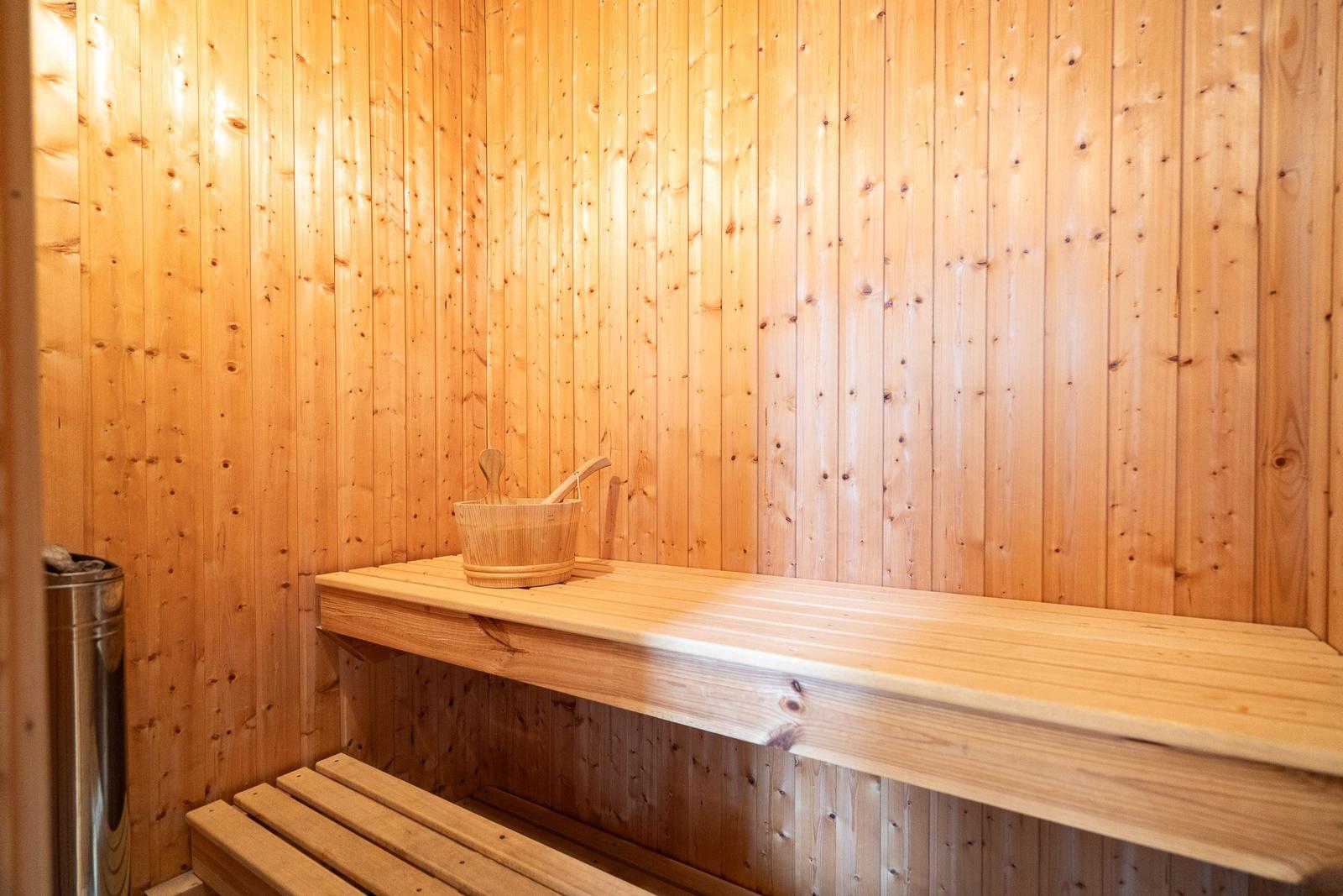 Sauna with wooden walls, bench, and wooden bucket with ladle.