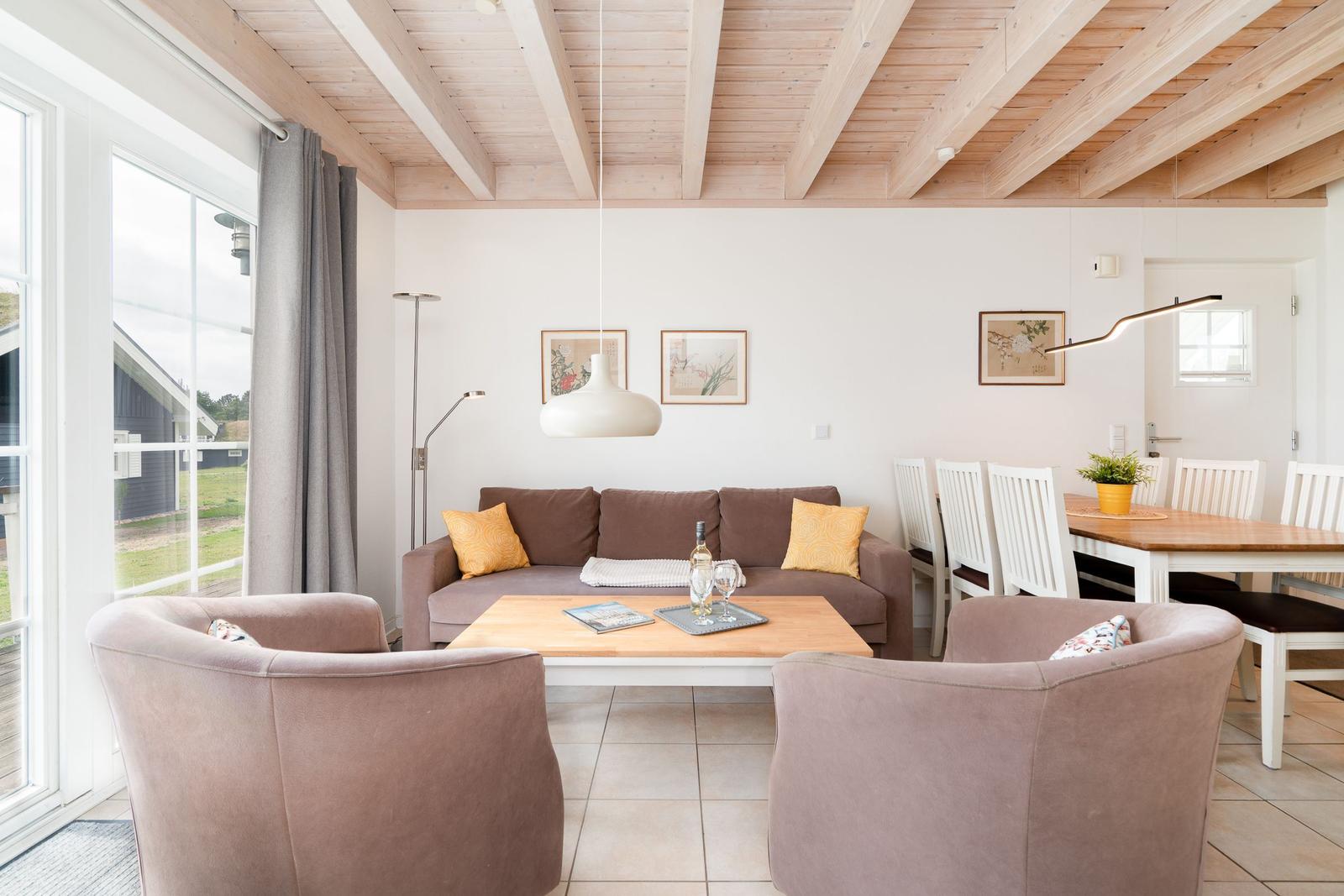 Living and dining area with sofa, two armchairs, and dining table with chairs.