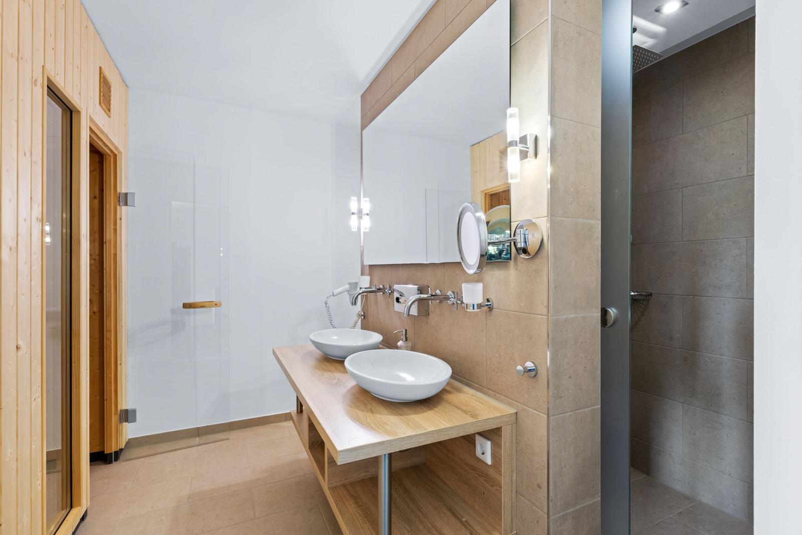 Bad mit zwei Waschbecken, Spiegel, Dusche und Sauna.
