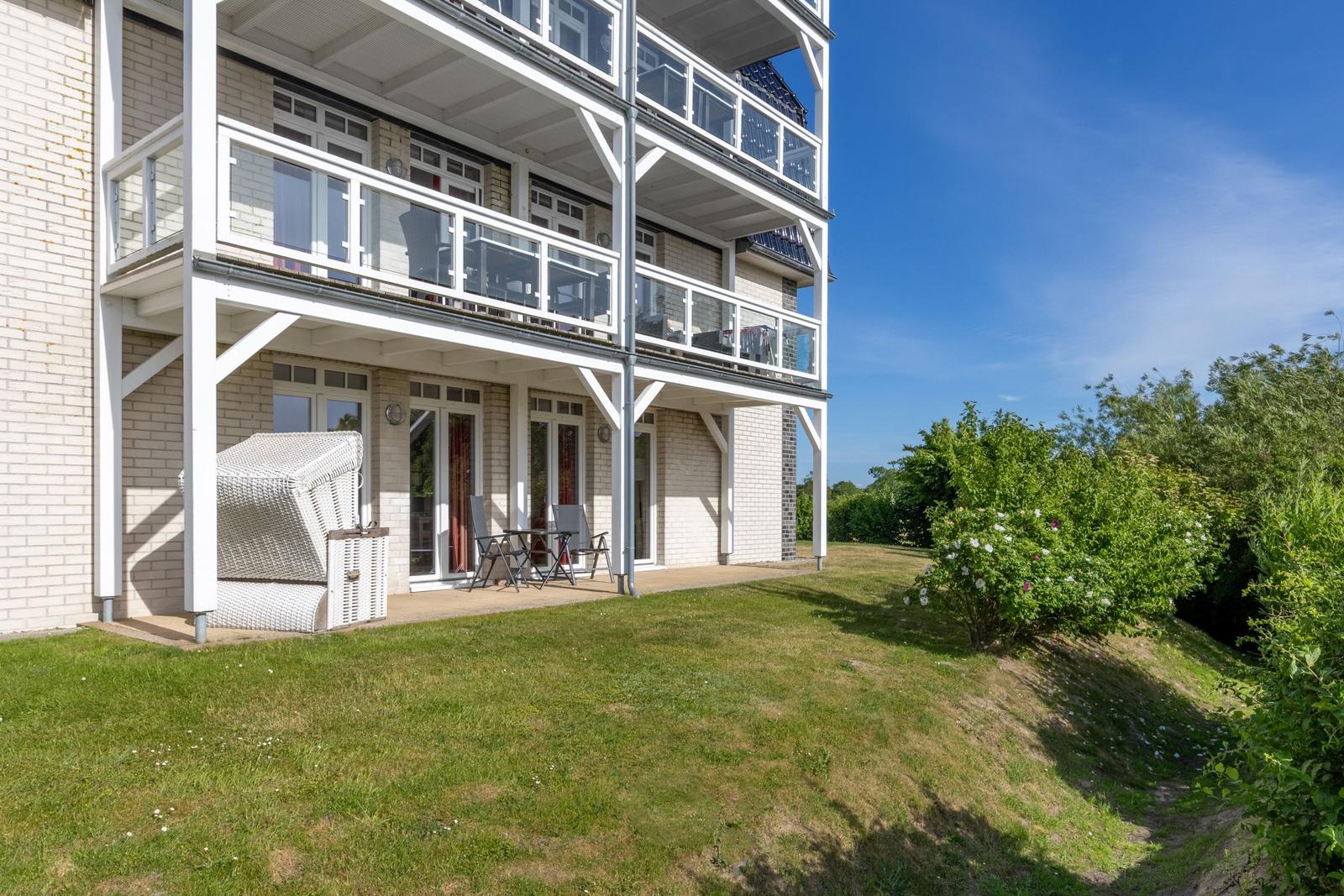 Haus mit Terrasse und Garten. Weiße Balkone und Grünflächen.