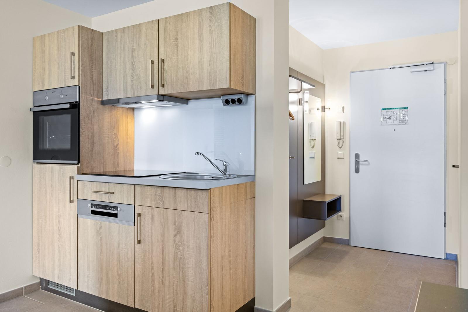 Küche mit Holzschränken, Spüle und integriertem Ofen und Waschmaschine
