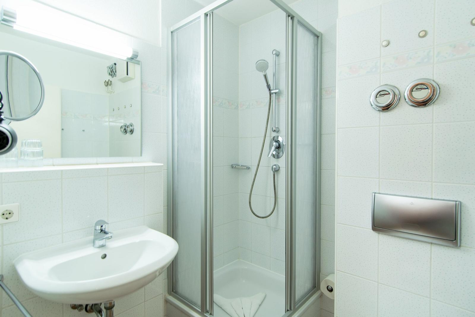 Badezimmer mit Dusche, Waschbecken und Spiegel