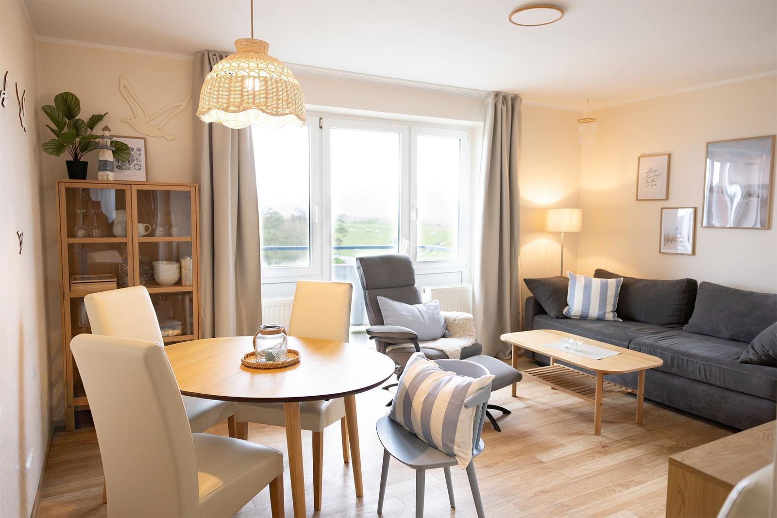 Wohn- und Essbereich mit Tisch, Stühlen, Sofa und Fenster.