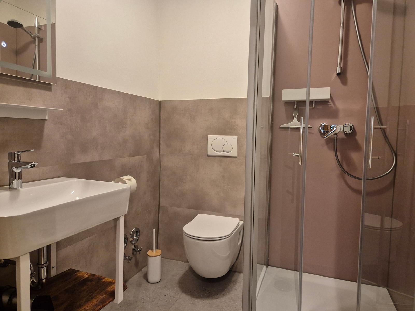 Badezimmer mit Dusche, Toilette und Waschbecken.