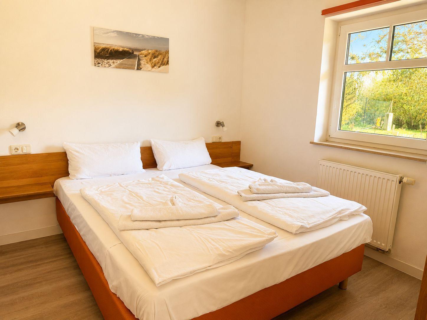 A bedroom with a double bed, window, and wall art.
