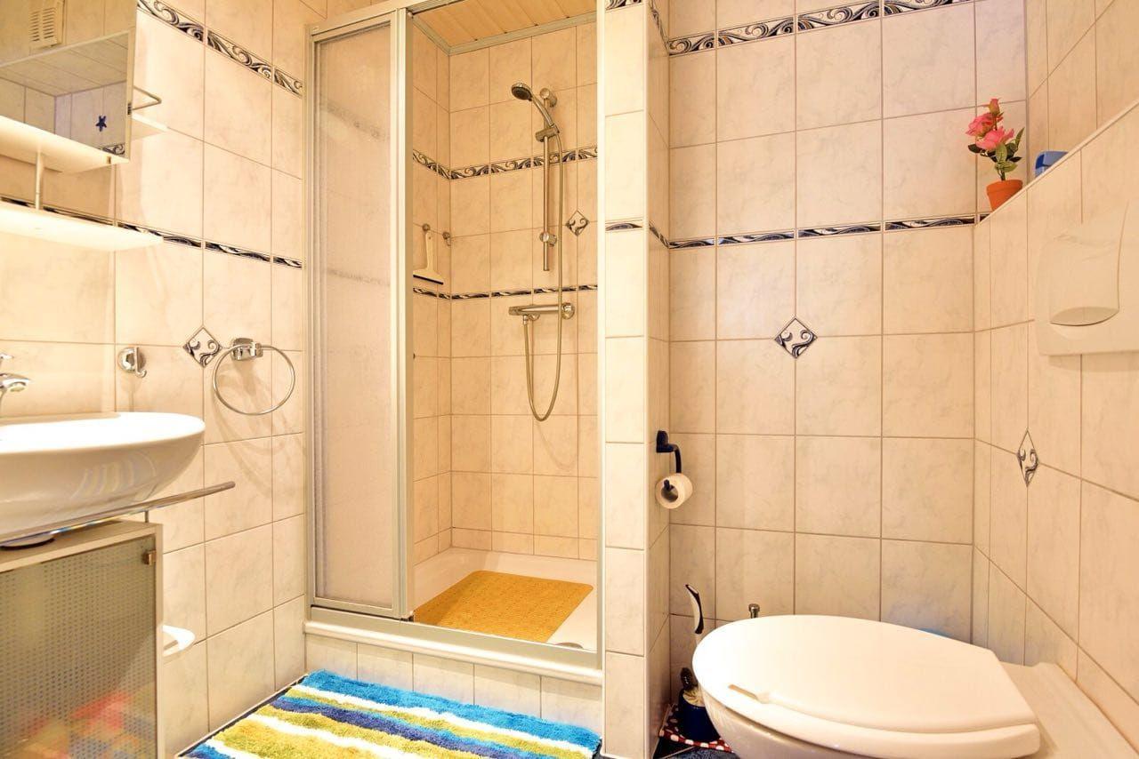 Bath with shower, sink, and toilet. Tiles with decorative stripes.
