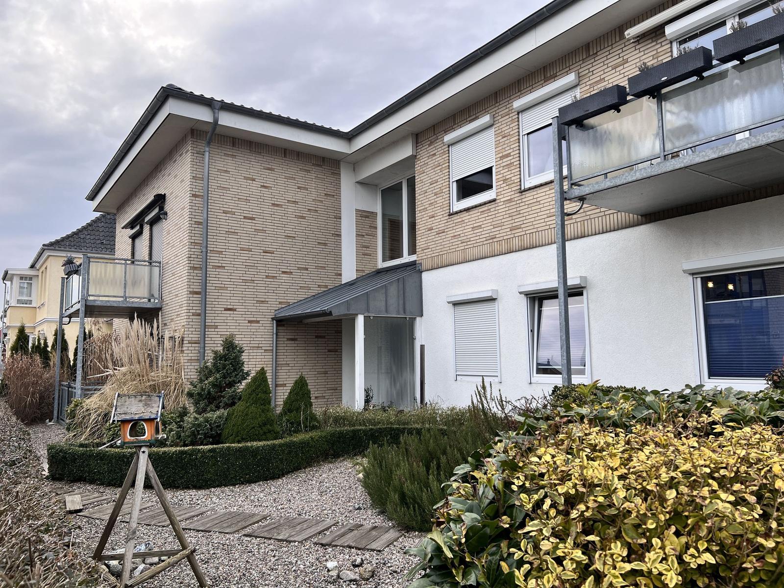 Moderne Wohnanlage mit Balkon, gepflegtem Garten und Holzweg.