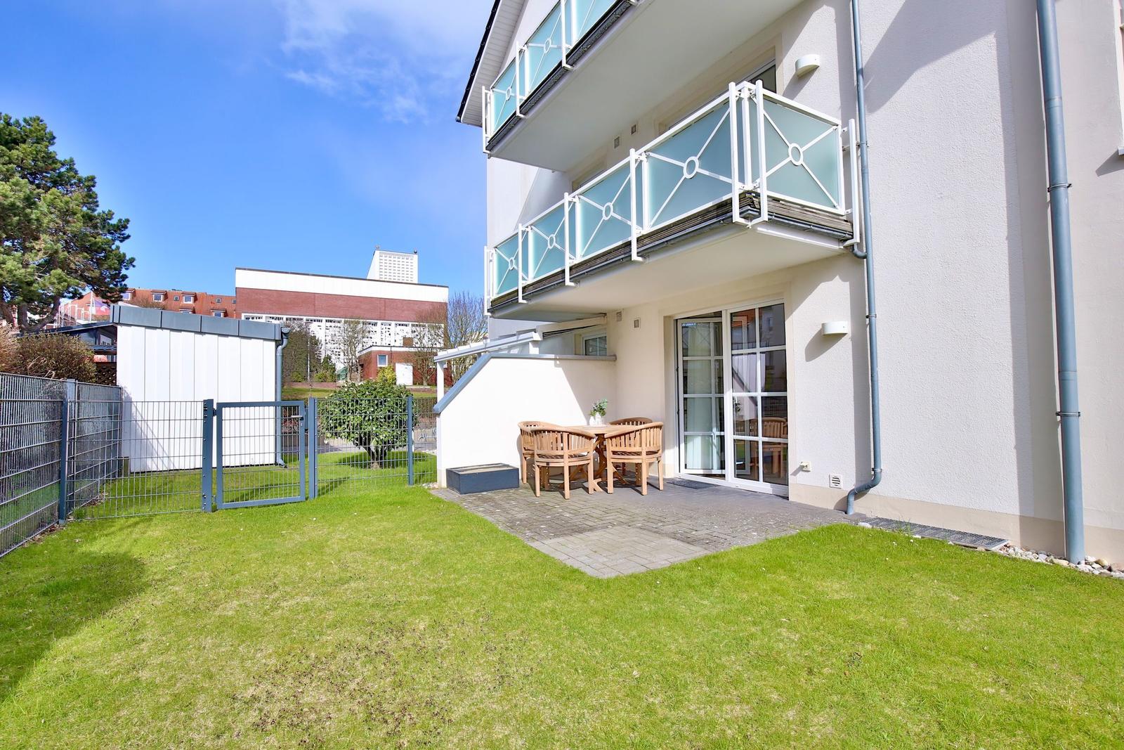 House with balcony, terrace and garden. Wooden table and chairs outside.