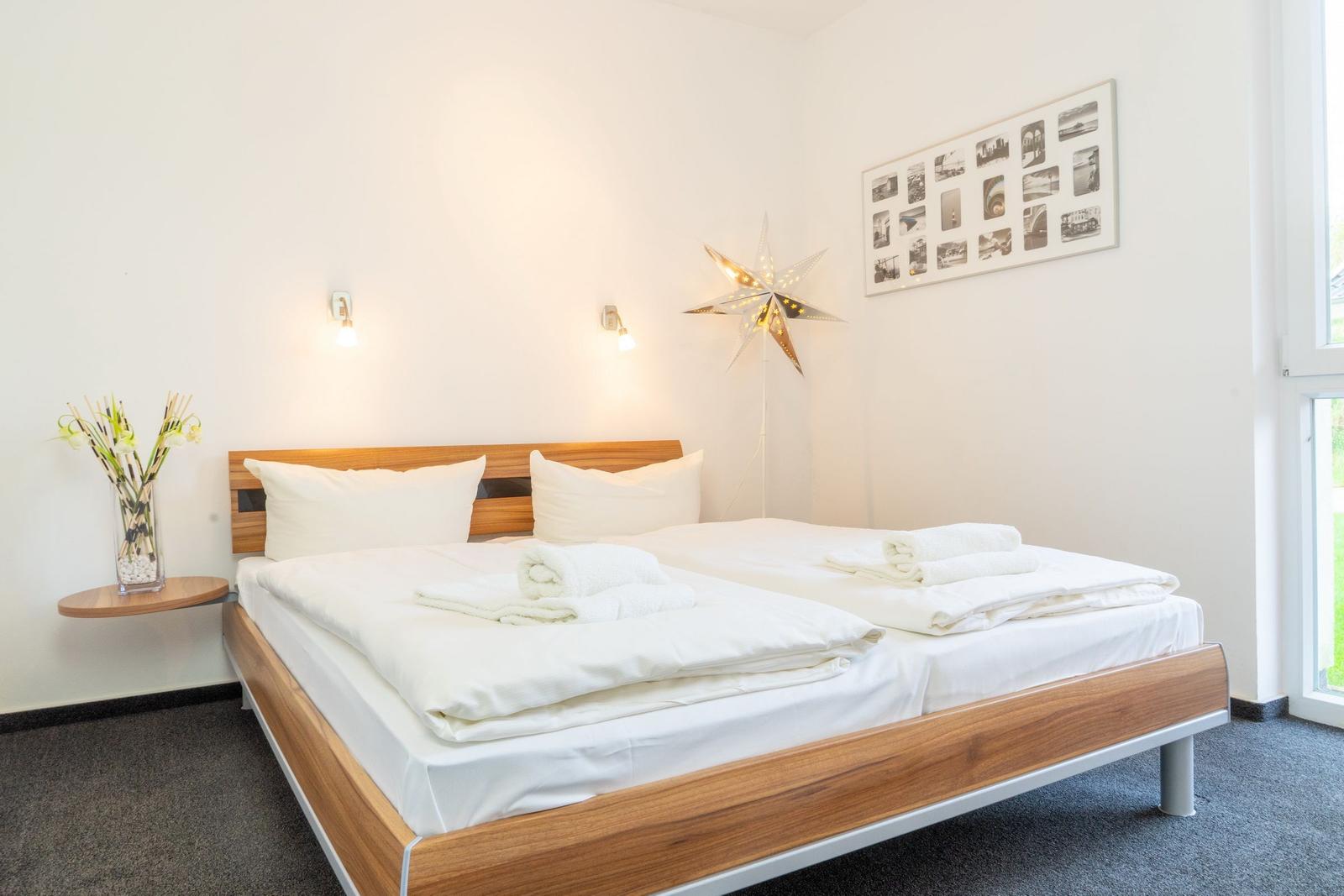 Ein Schlafzimmer mit einem Bett, einer Wandlampe und einem Fenster.