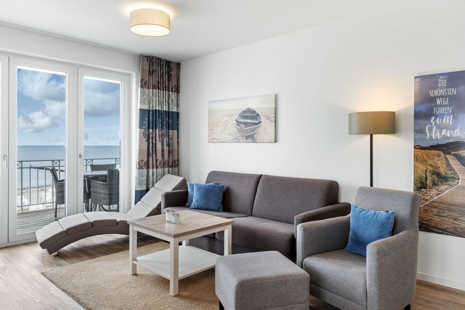 Wohnzimmer mit Sofa, Sessel und Blick auf den Strand