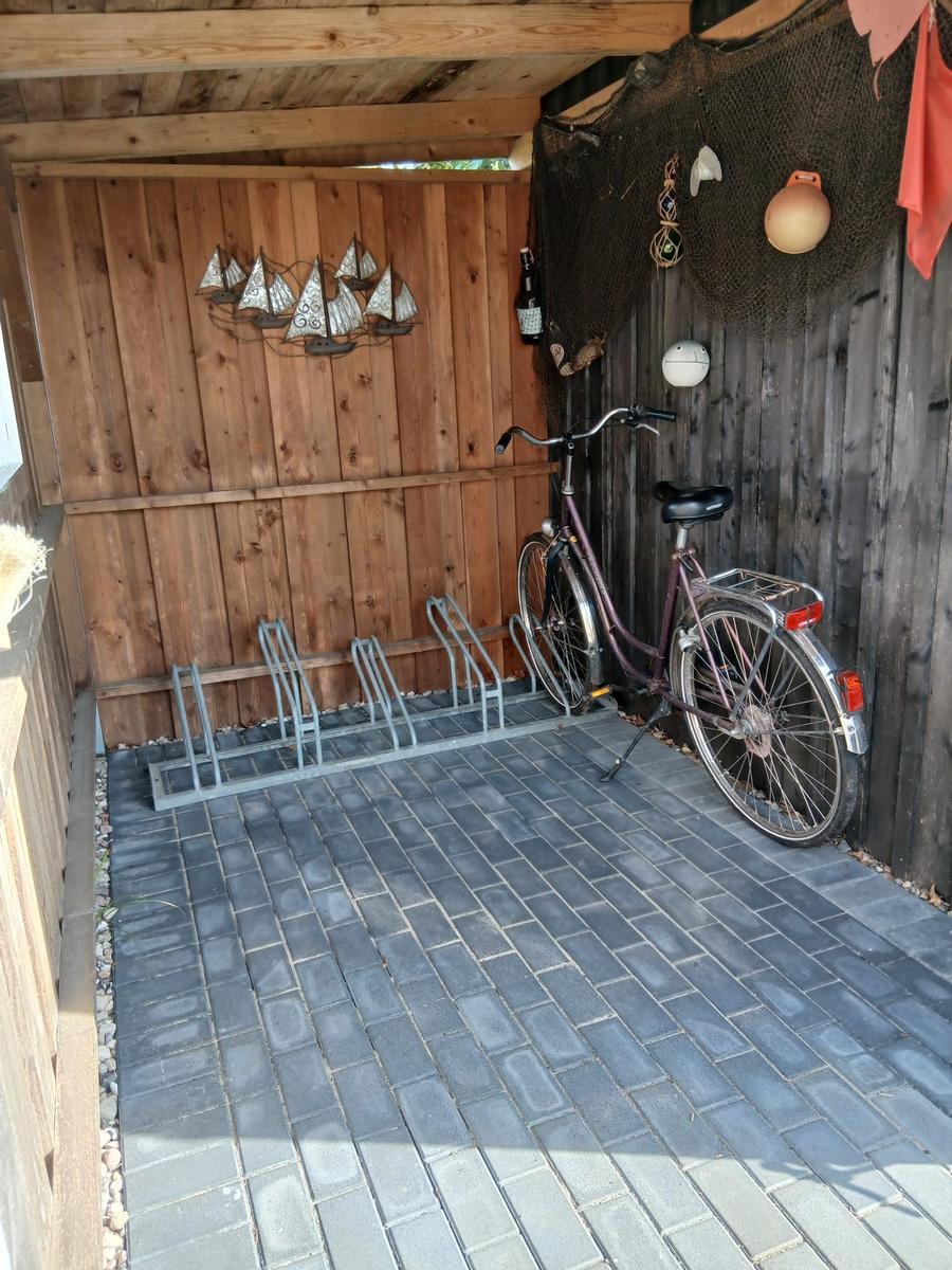 Ein Fahrrad steht in einer Garage mit Holzwand und Boden aus grauen Pflastersteinen.