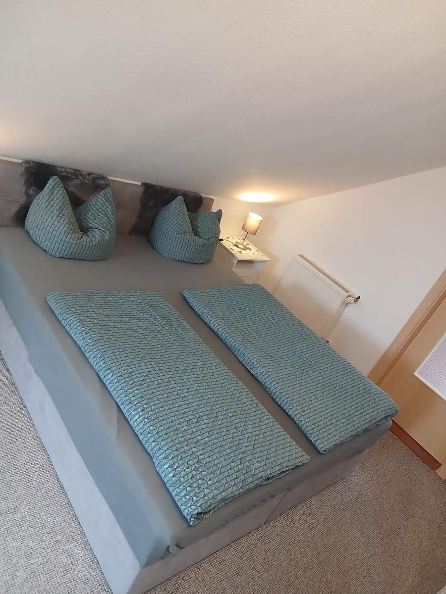 Schlafzimmer mit Bett, zwei Kissen und Nachttisch mit Lampe.