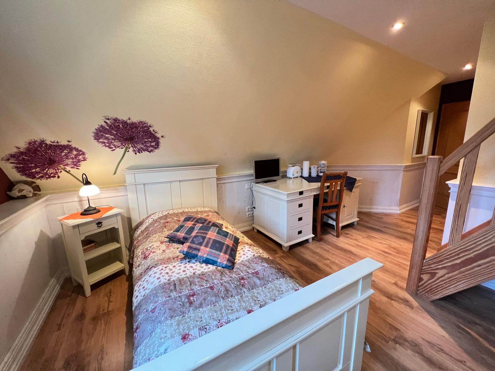 Schlafzimmer mit Bett, Schreibtisch und Wanddekoration