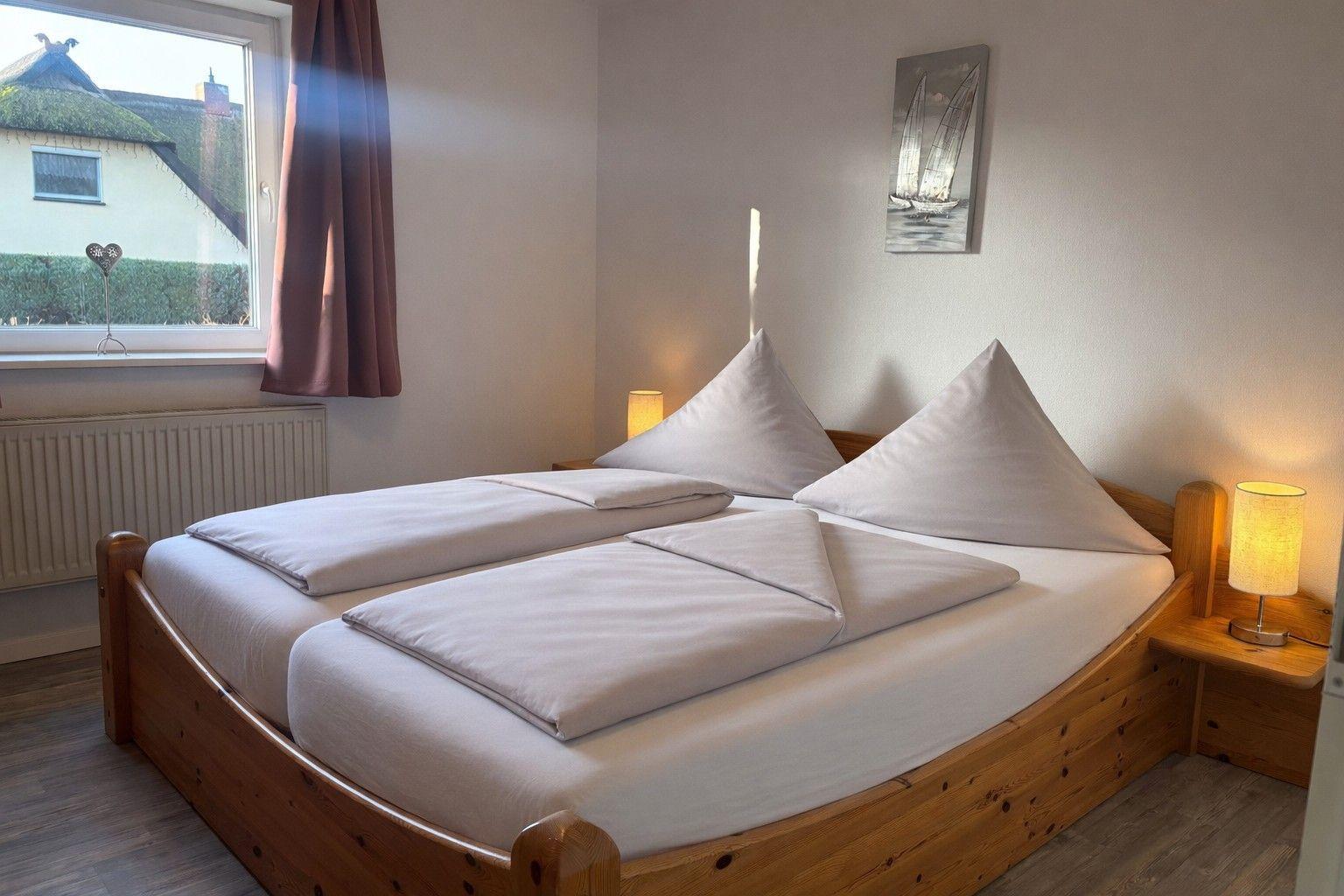 Ein Schlafzimmer mit einem Doppelbett, zwei Nachttischen und einem Fenster mit Blick auf eine Straße.