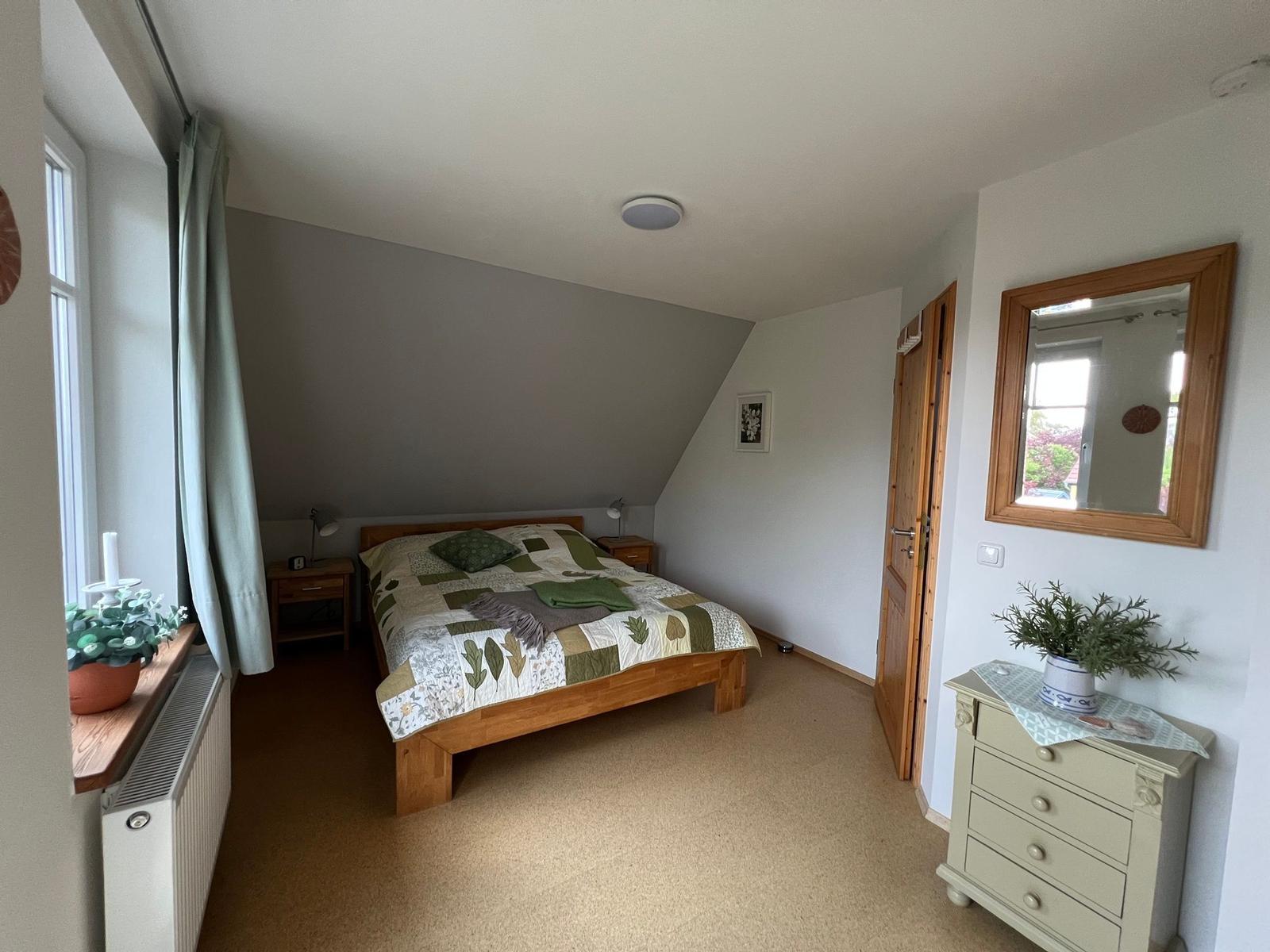 Schlafzimmer mit Holzbett, Nachttischen und Spiegelschrank