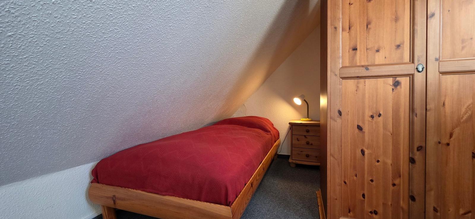 Ein Schlafzimmer mit einem Bett, einem Kleiderschrank und einer Nachttischlampe.