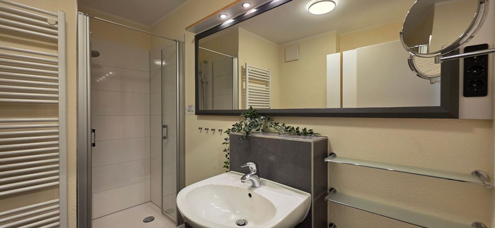 Badezimmer mit Dusche, Waschbecken und Spiegel