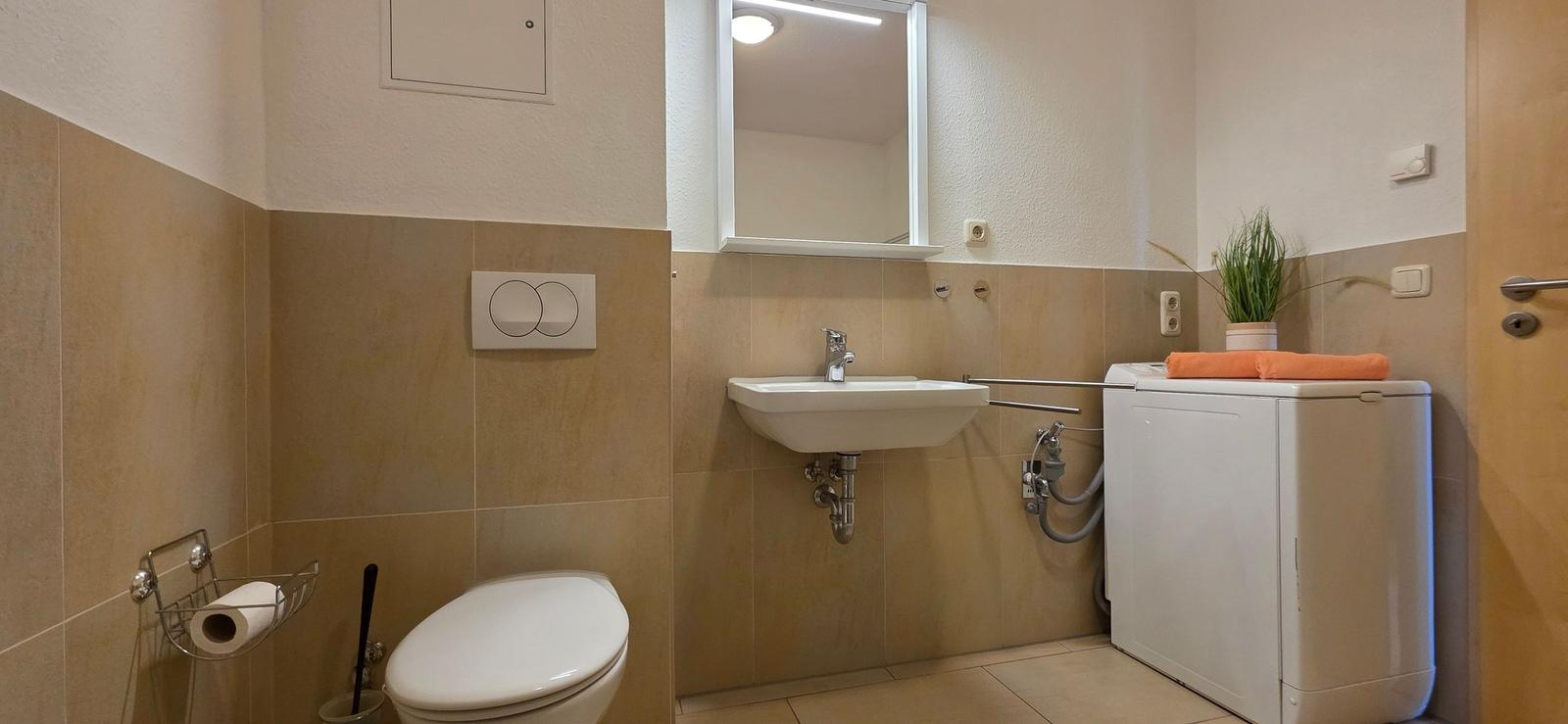 Badezimmer mit Toilette, Waschbecken und Waschmaschine.