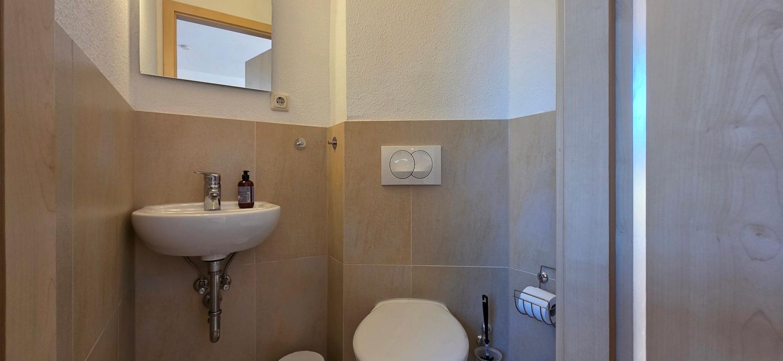 Badezimmer mit Waschbecken, Toilette und Spiegel an der Wand.