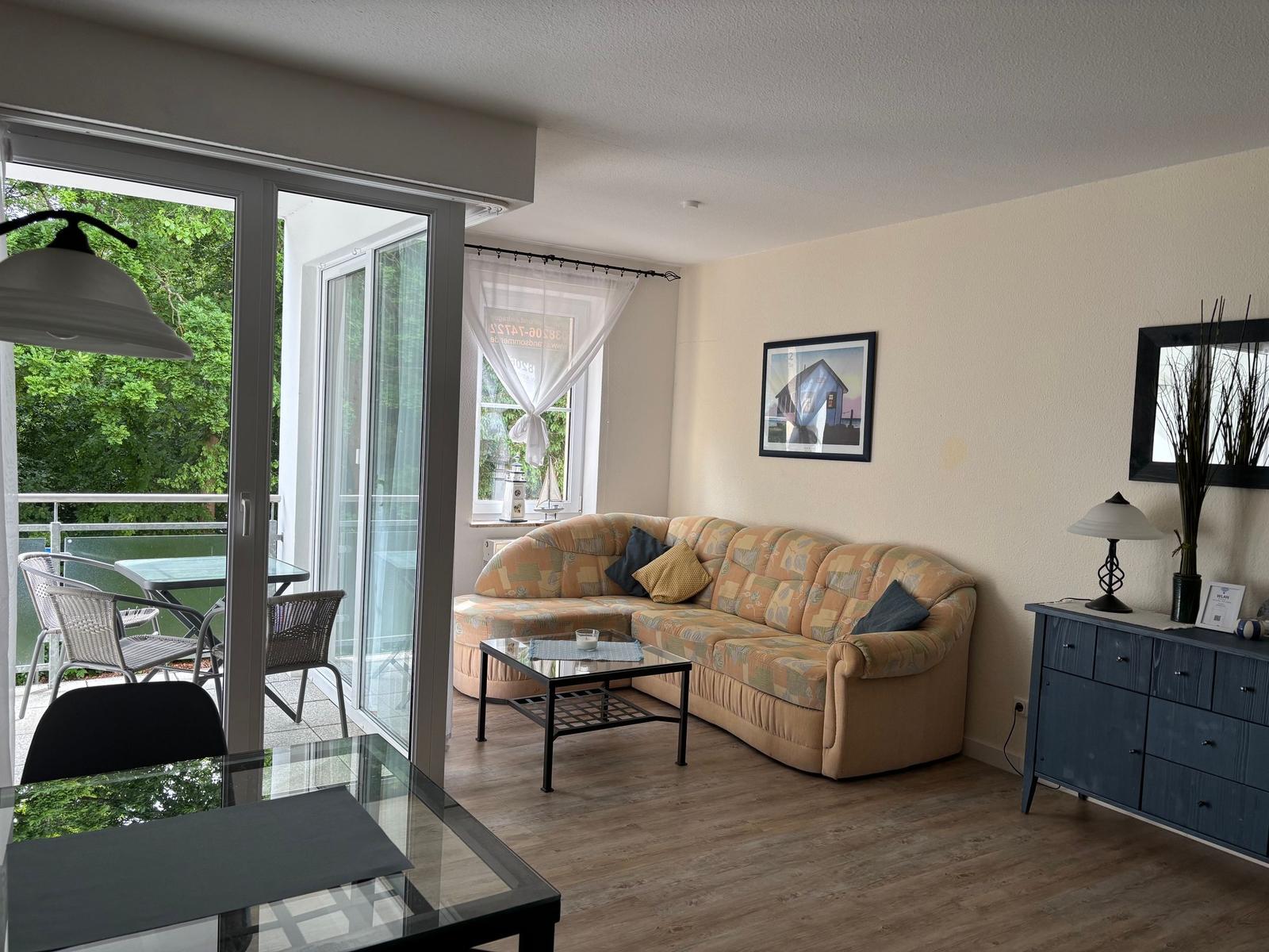 Wohnzimmer mit Sofa, Couchtisch und Terrasse mit Gartenblick.