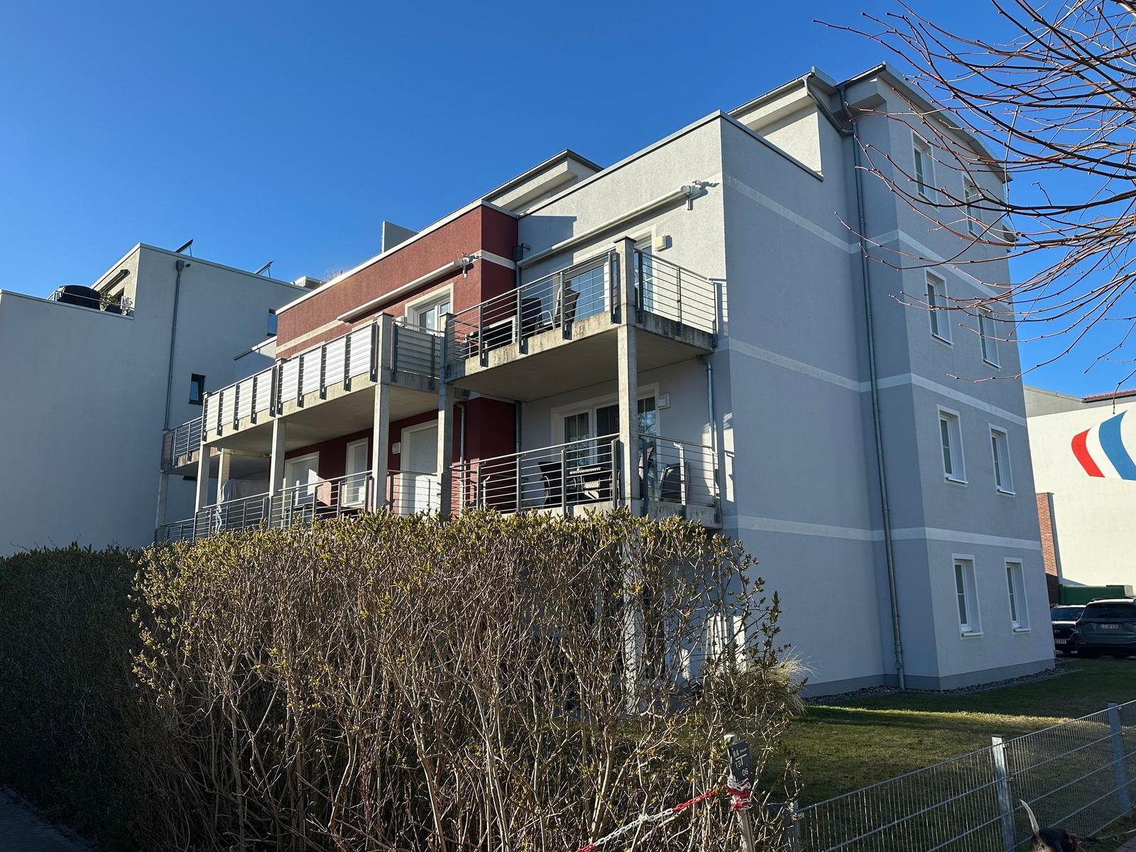 Modernes Mehrfamilienhaus mit Balkonen und grüner Umgebung.