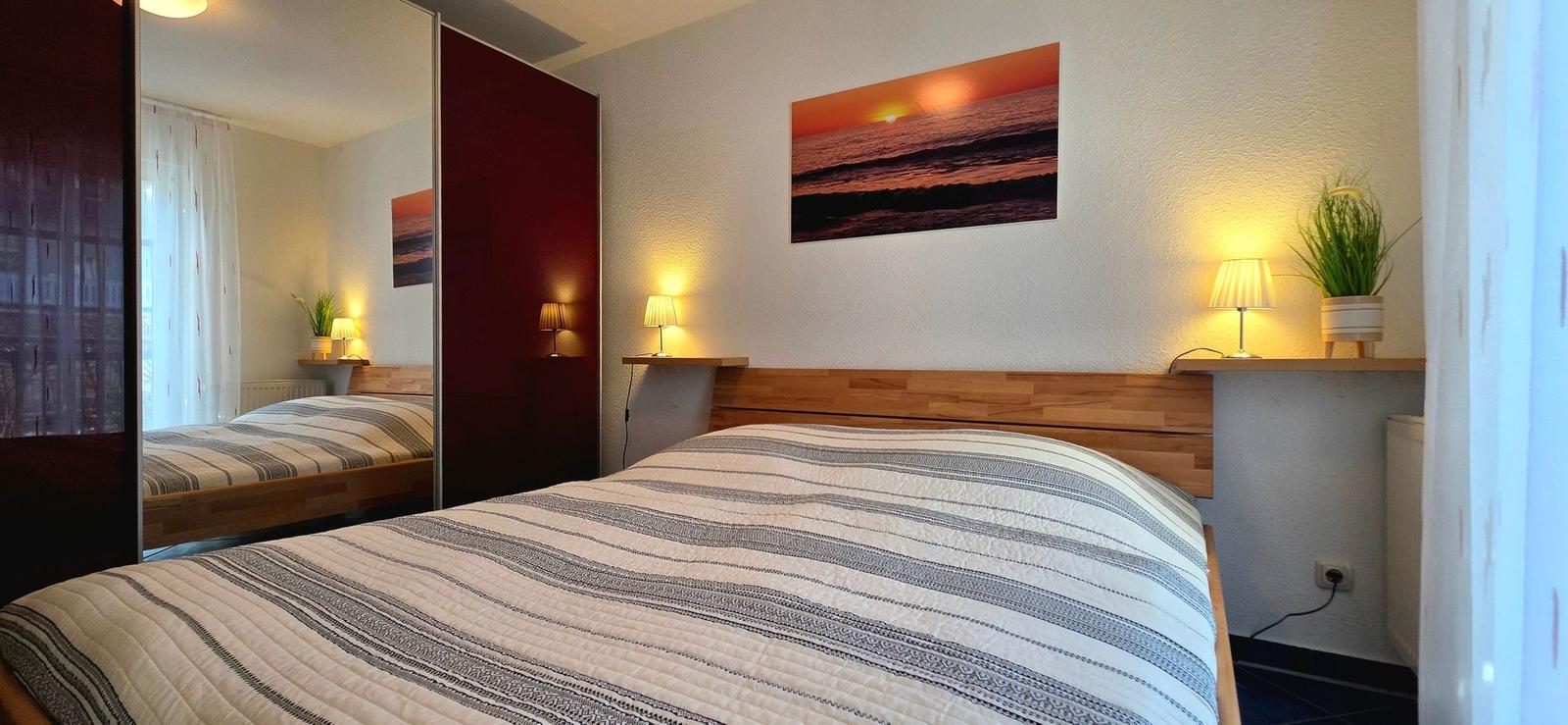 Schlafzimmer mit Bett, Wandbild und Nachttischlampen