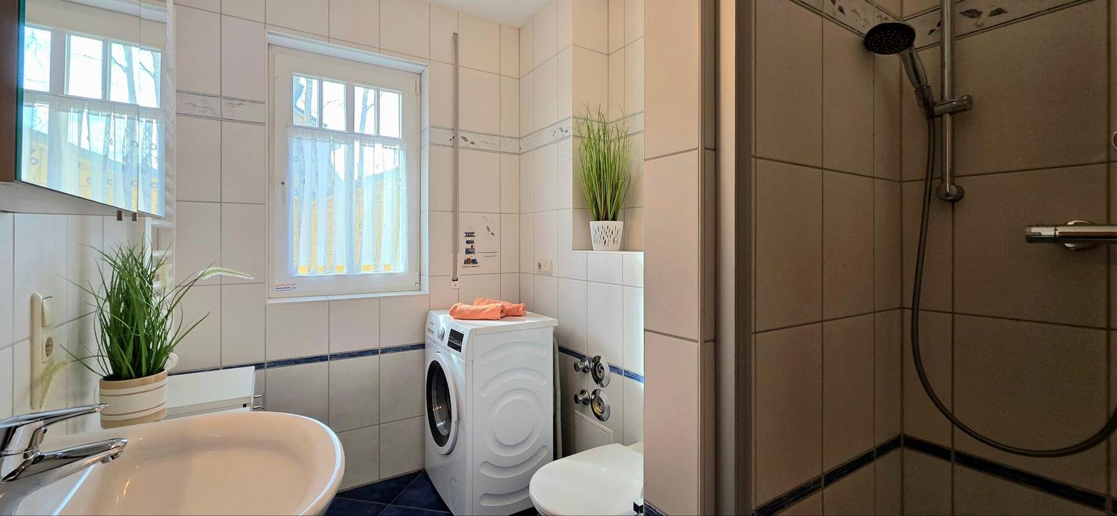 Badezimmer mit Dusche, Waschmaschine und Fenster