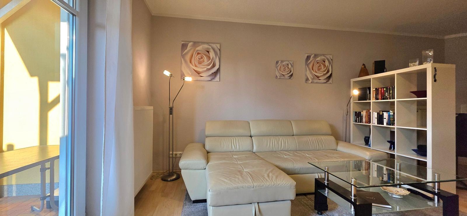 Living room with cream sofa, glass table, and bookshelf on the wall.