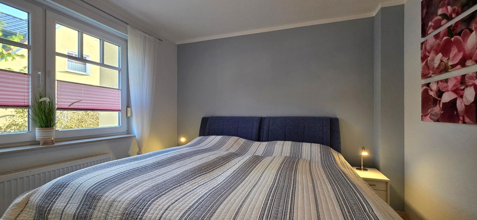 Bedroom with bed, window, and wall art.