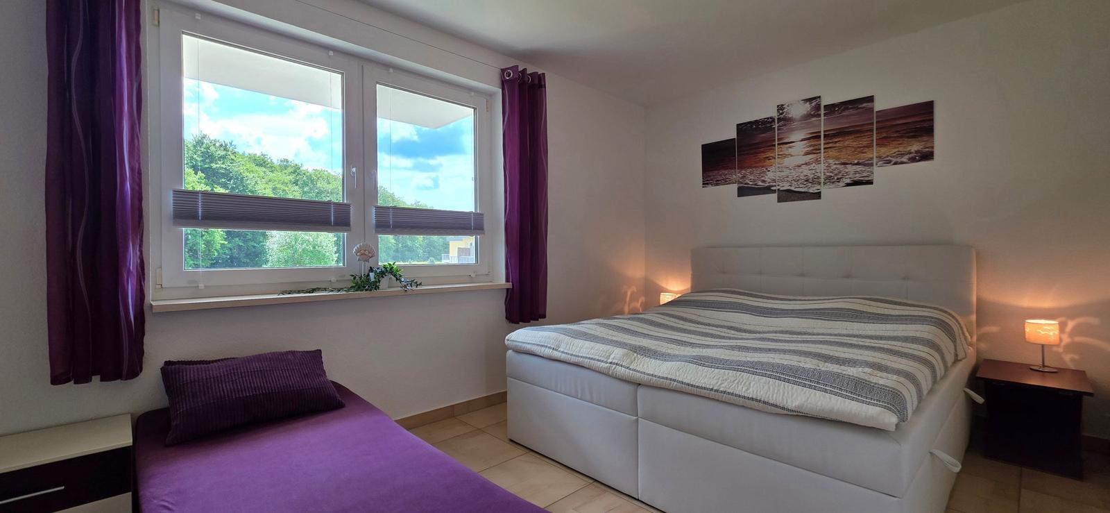 Schlafzimmer mit Doppelbett, Fenster und Wandbild