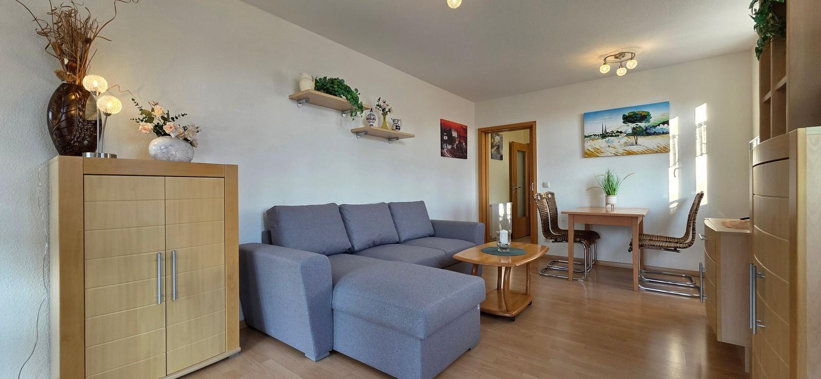 Wohn- und Essbereich mit Sofa, Tisch und Stühlen sowie Holzmöbeln.