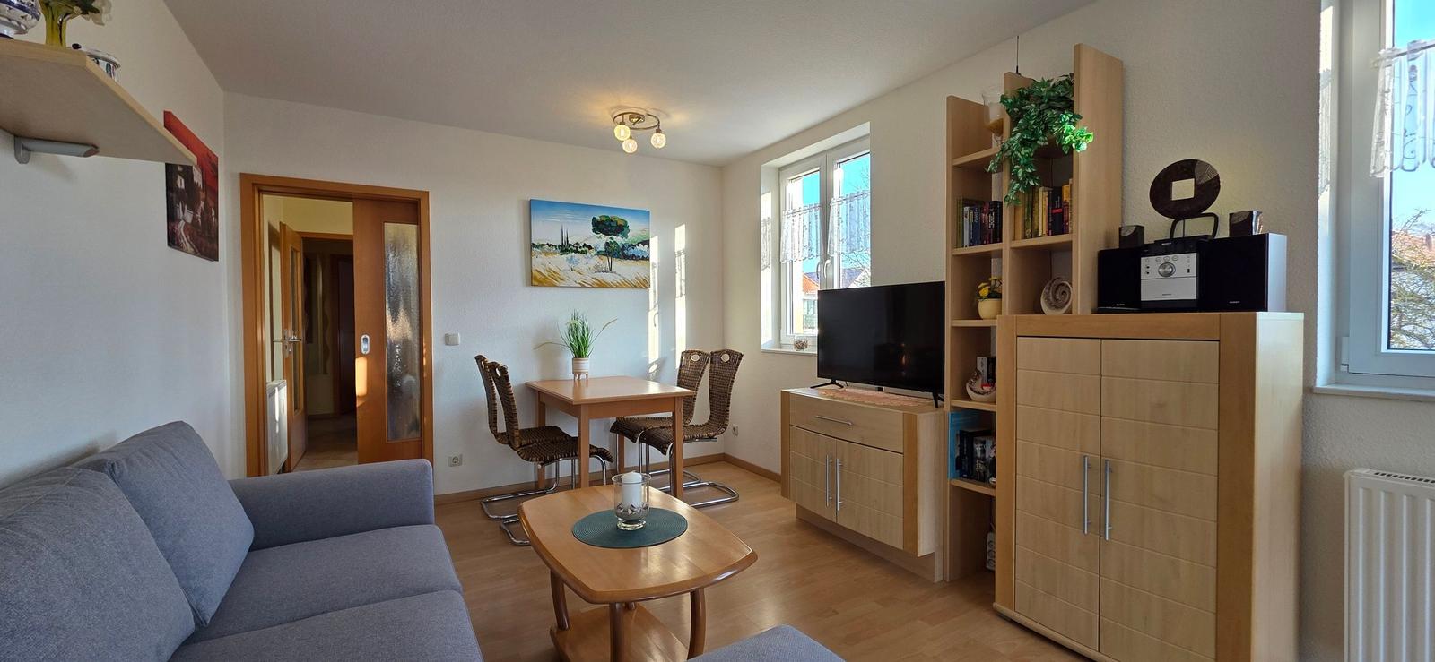 Wohn- und Essbereich mit Sofa, Esstisch, TV und Holzmöbel.