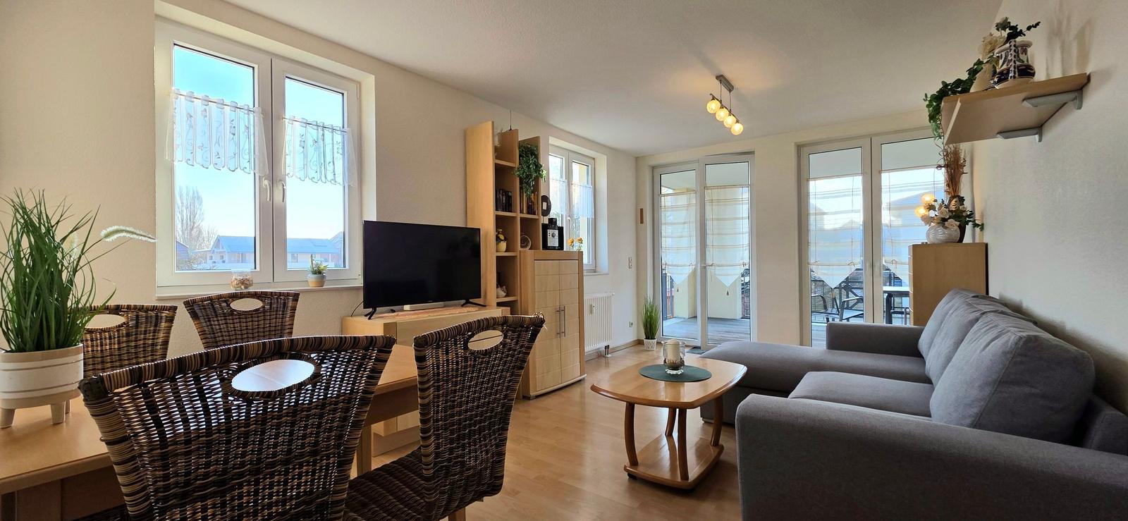 Wohn- und Essbereich mit Sofa, TV und Essgruppe. Durchgang zur Terrasse.