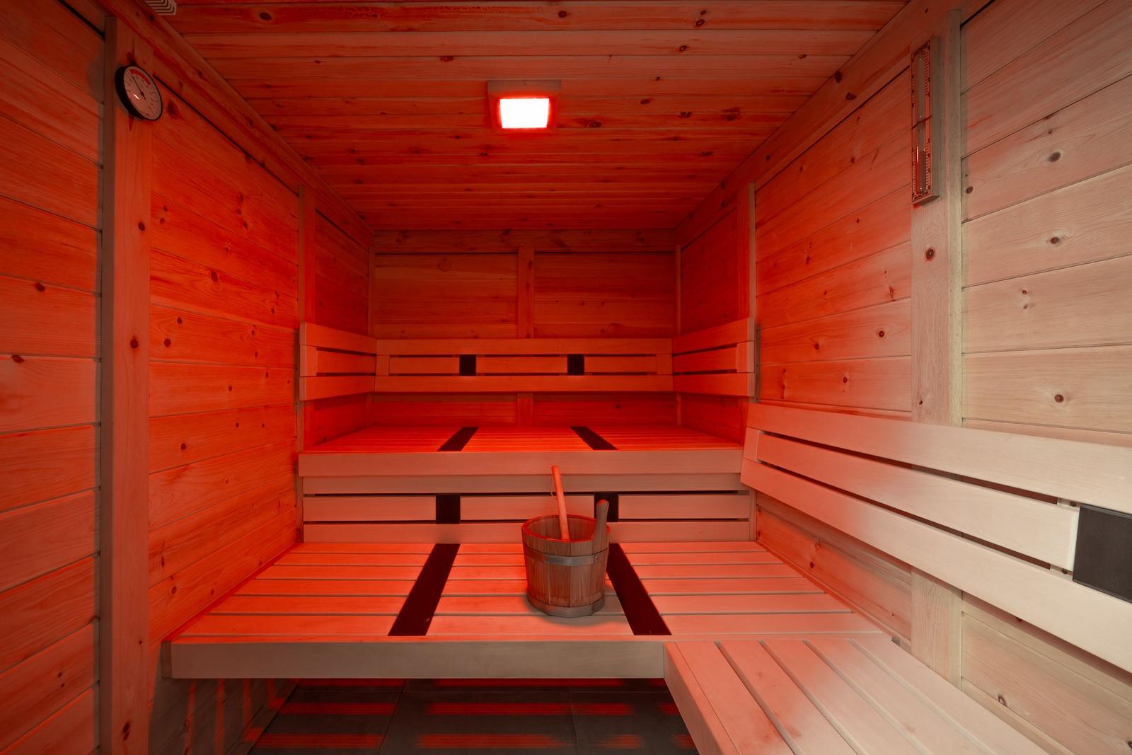 Sauna with wooden bench, thermometer, and bucket with ladle.