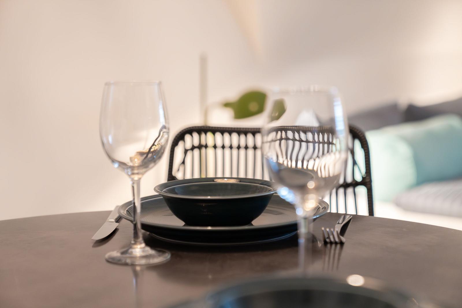 Table set with plate, bowl, fork, and knife. In background chair and sofa.