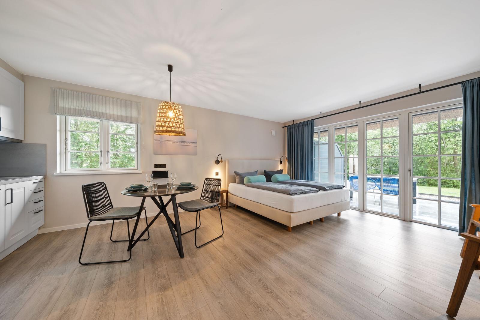 Schlafzimmer mit Bett, Esstisch und Terrassenzugang.