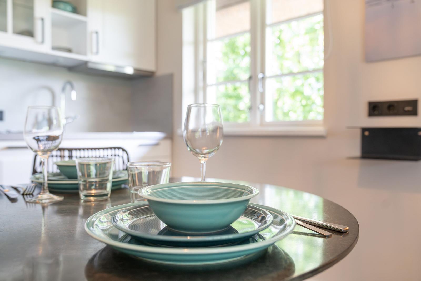 Kücheninsel mit Tischset, Fenster und weißen Schränken