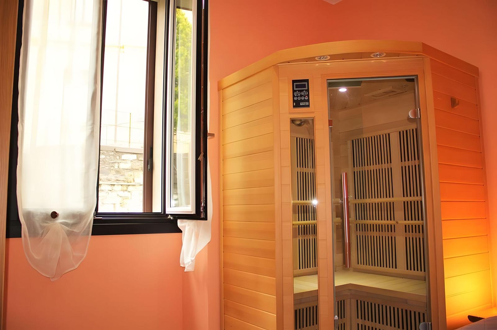 Sauna with wooden cladding and window with curtains on orange wall.