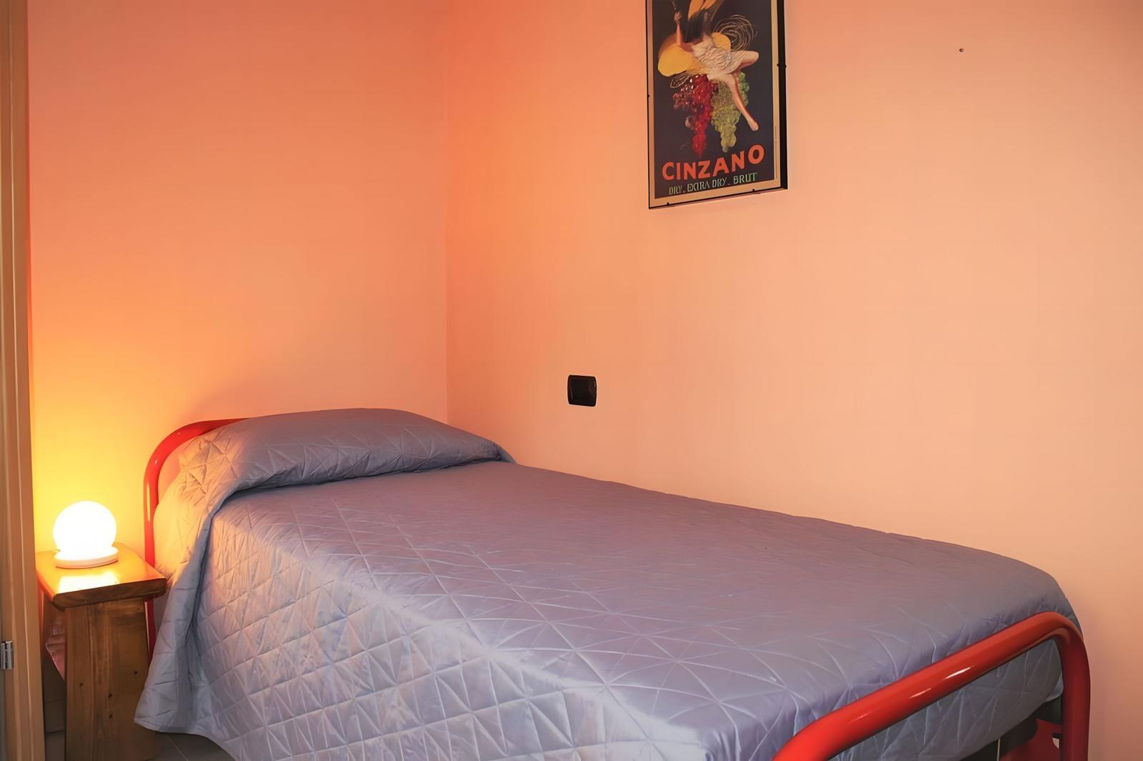 A bed with blue bedding and red frame. A poster hangs on the wall.