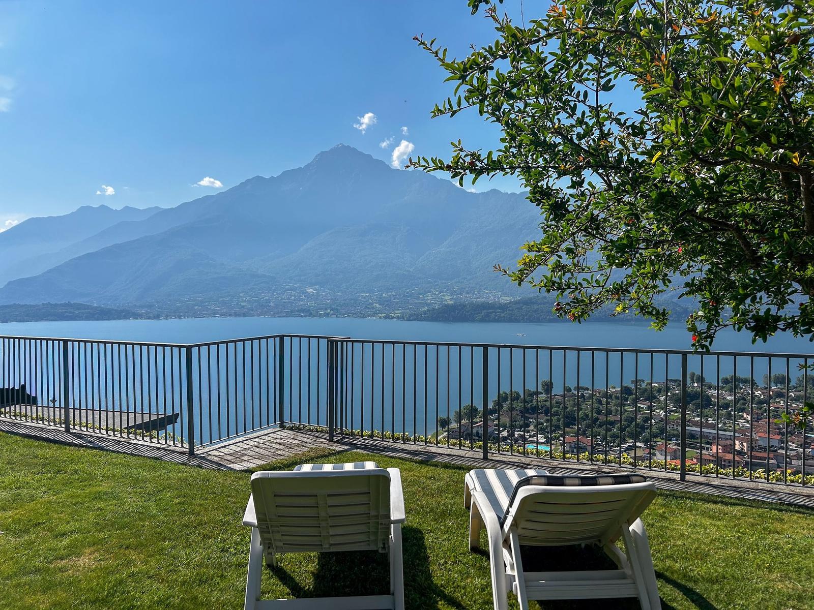 Terrasse mit Liegestühlen und Blick auf See und Berge.
