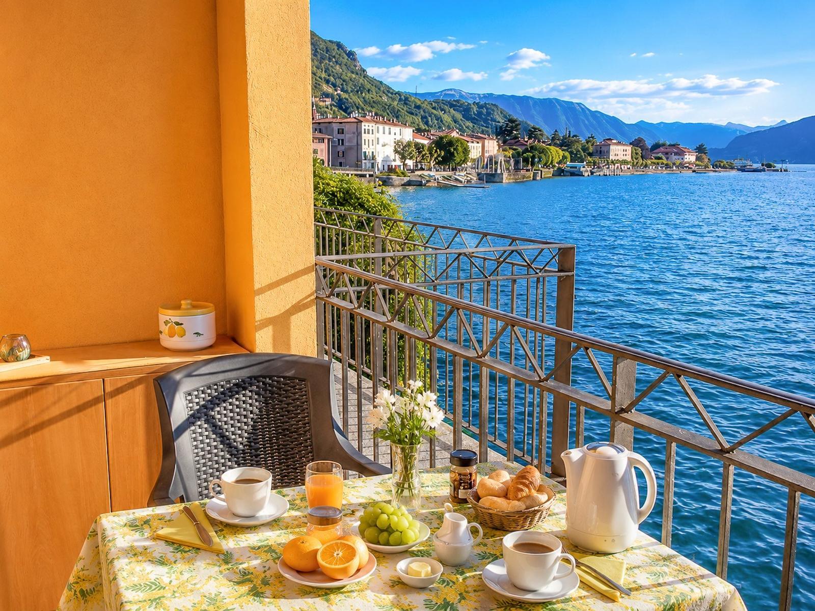 Frühstückstisch auf Balkon mit Blick auf See und Berglandschaft.