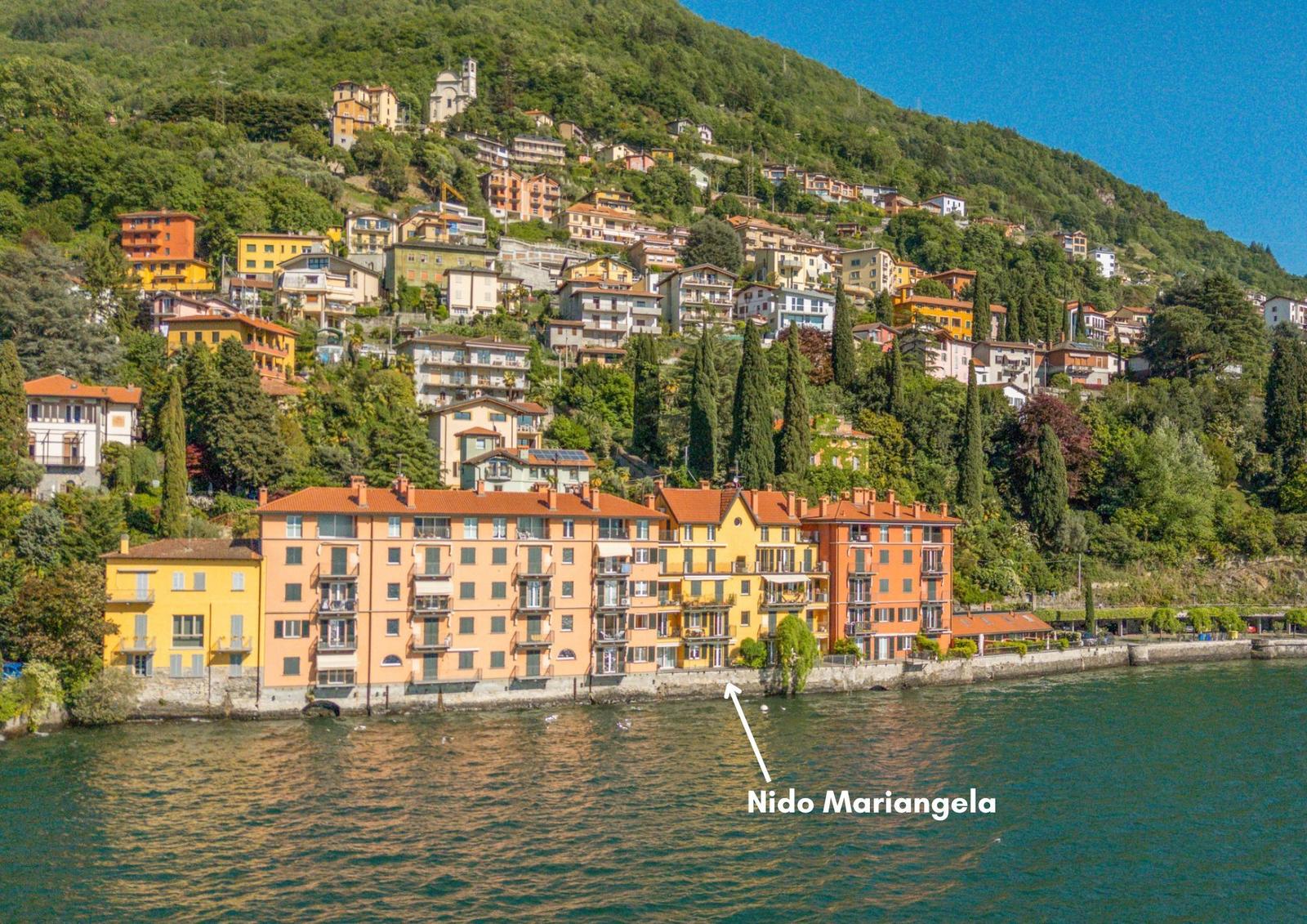 Nido Mariangela liegt an einem Seeufer mit Blick auf eine bergige Stadt.