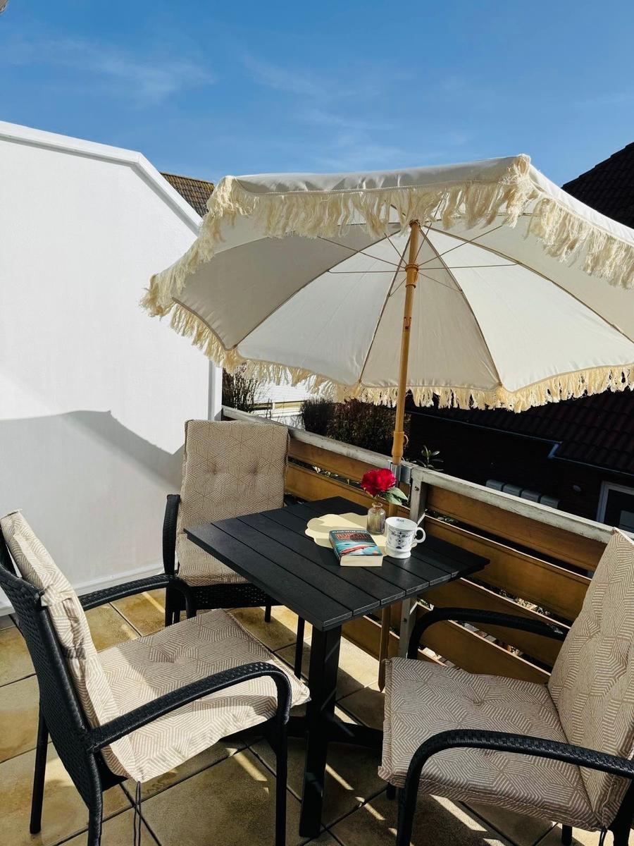 Terrace with table, three chairs, and umbrella with fringe.